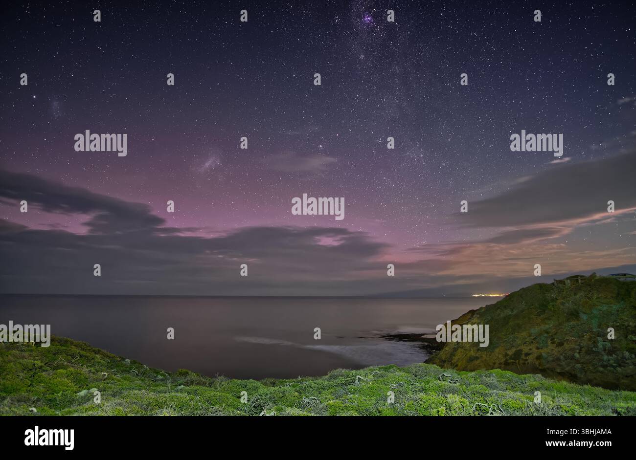 Nachthimmel mit Milchstraße und leichter aurora über Küste und Ozean mit Horizont und Wolken am Point Addis, Victoria, Australien Stockfoto