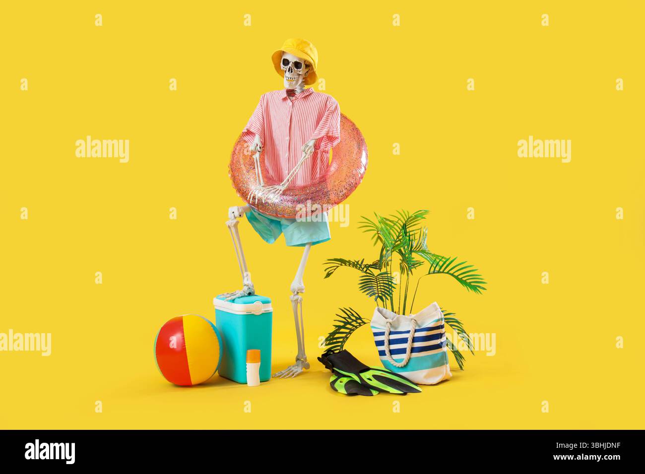 Menschliches Skelett mit Strandzubehör auf gelbem Hintergrund Stockfoto