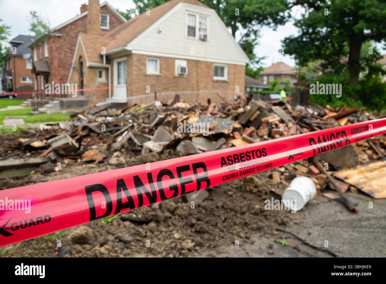 Detroit, Michigan - Schilder warnen vor Asbestgefahr, wenn ein Haus abgerissen wurde. Das Haus war ein Jahr zuvor durch einen Brand schwer beschädigt worden und war eine ne Stockfoto