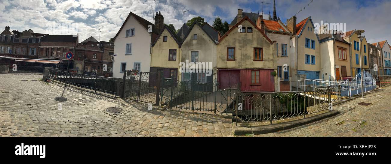 Panoramablick auf eine malerische Straße, die mit Gebäuden im Vintage-Stil geschmückt ist und die lebhafte Architektur unter einem teilweise bewölkten Himmel zeigt. Stockfoto