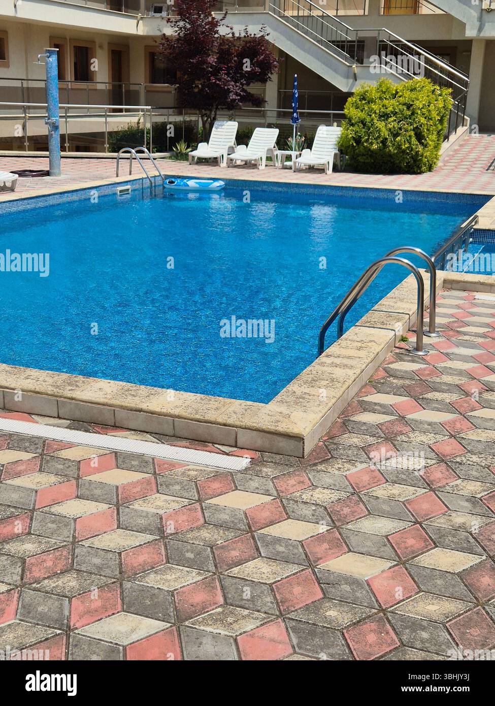 Außenpool mit klarem blauem Wasser, Liegestühlen, Sonnenschirmen. Luxuriöser Pool - Smartphone-aufgenommenes Stockfoto