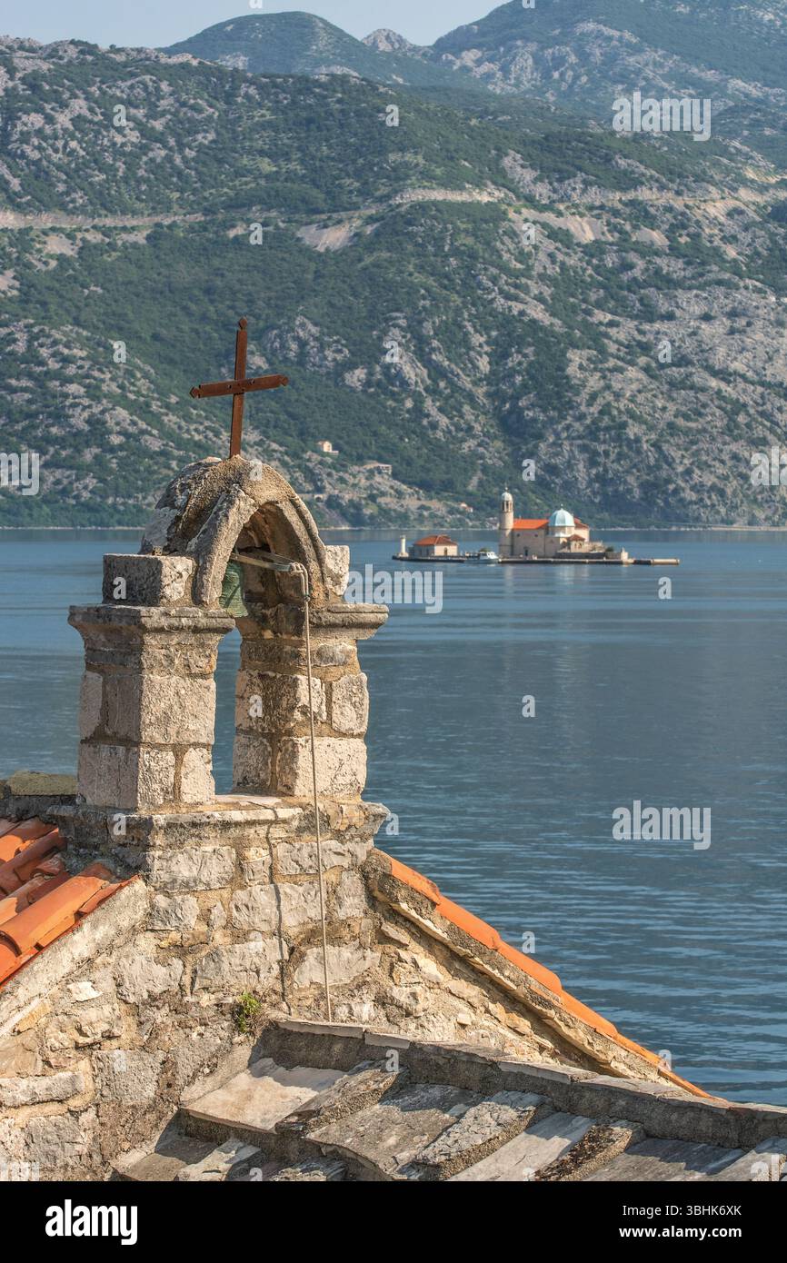Perast Stadt, Inselkirche, „unsere Lieben Frau der Felsen“ mit dem Glockenturm der Kirche „unsere Lieben Frau der Engel“ auf Verige, Stoliv, im Vordergrund. Stockfoto
