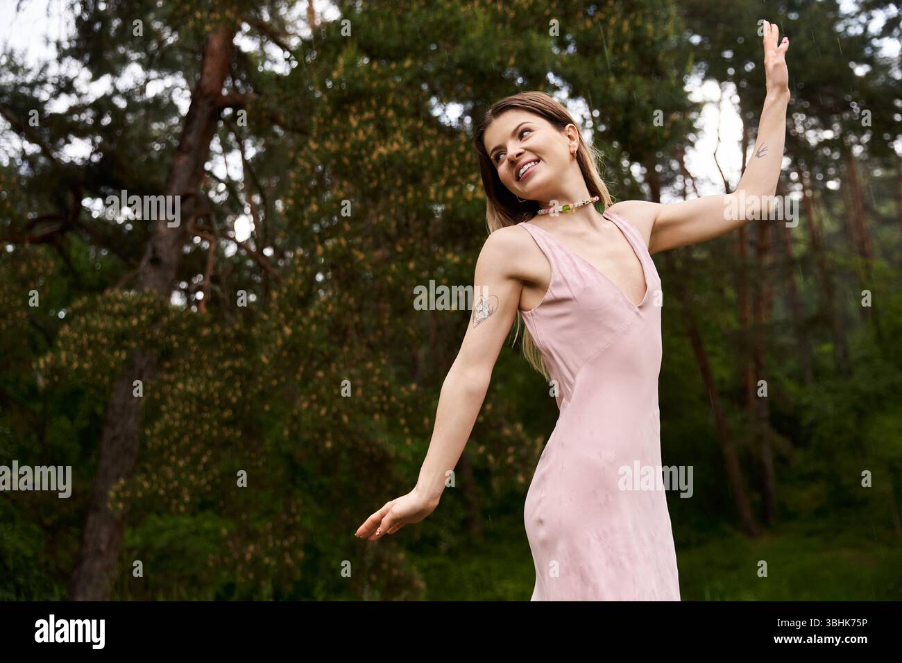 Eine junge Frau in einem hellen Kleid tanzt im Wald. Stockfoto