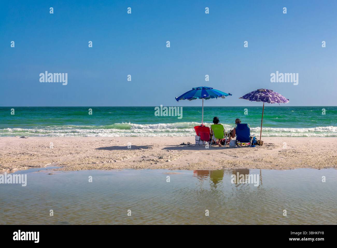 Ein paar Leute mit Liegestühlen und Sonnenschirmen am Siesta Beach in Siesta Key, Sarasota, Florida Stockfoto
