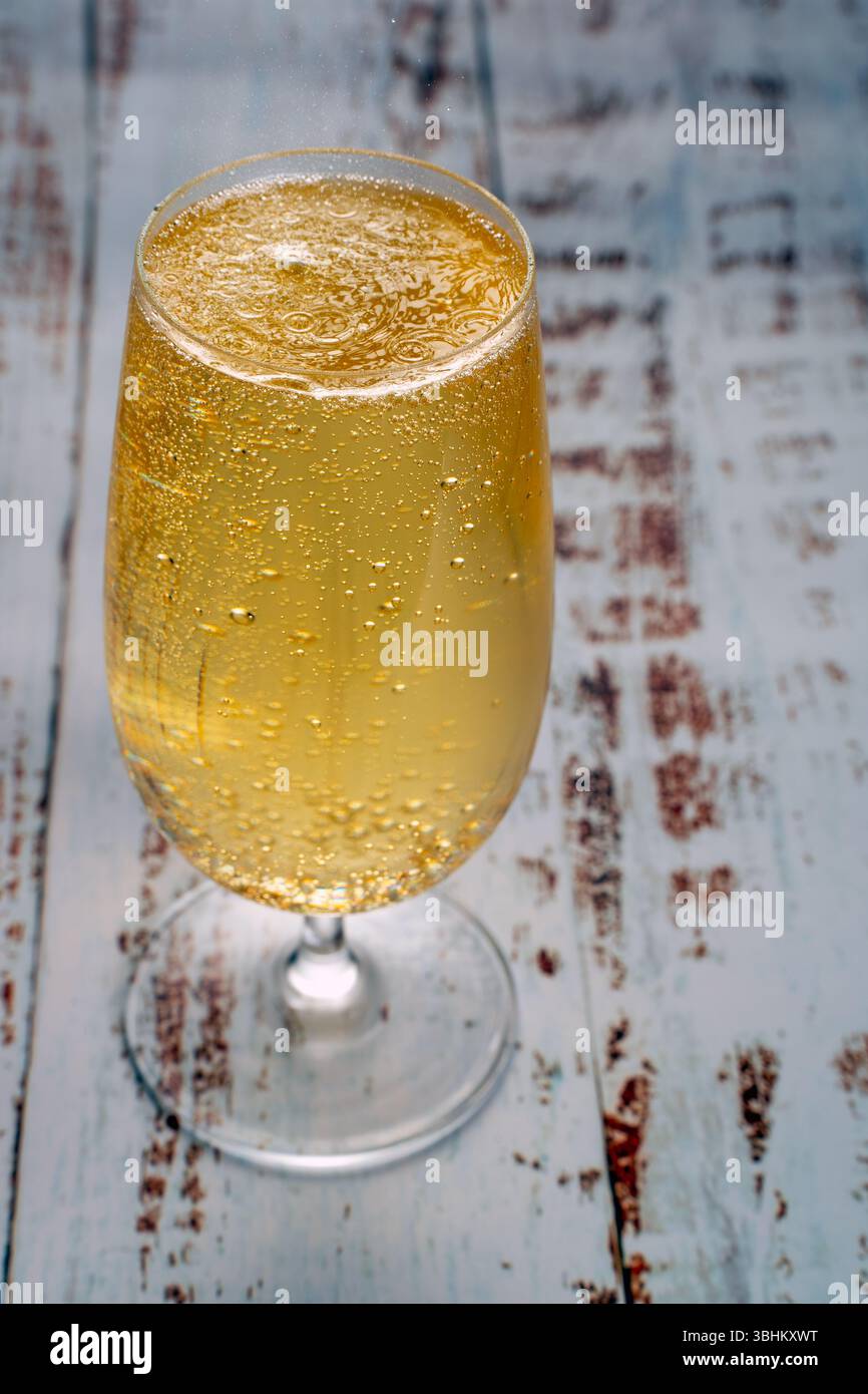 Eine Nahaufnahme von goldenem Bier in Stängelglas mit zahlreichen kleinen Blasen, die auf einem strukturierten Hintergrund an die Oberfläche steigen. Konzept des Feierns Stockfoto