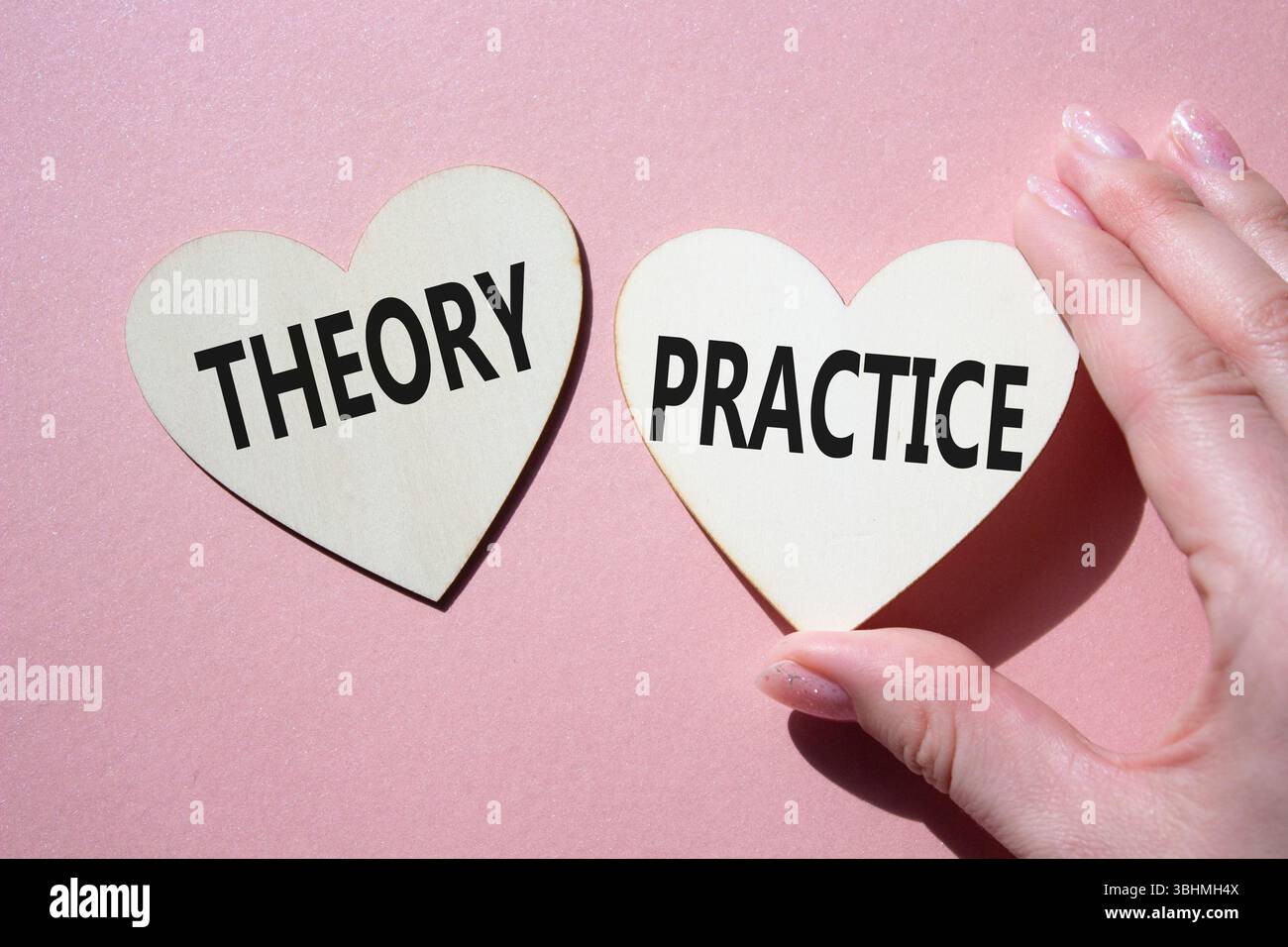 Theorie- oder Praxissymbol. Konzeptwort Theorie oder Praxis auf hölzernen Herzen. Geschäftsmann Hand. Schöner rosafarbener Hintergrund. Business und Theorie oder Praxis Stockfoto