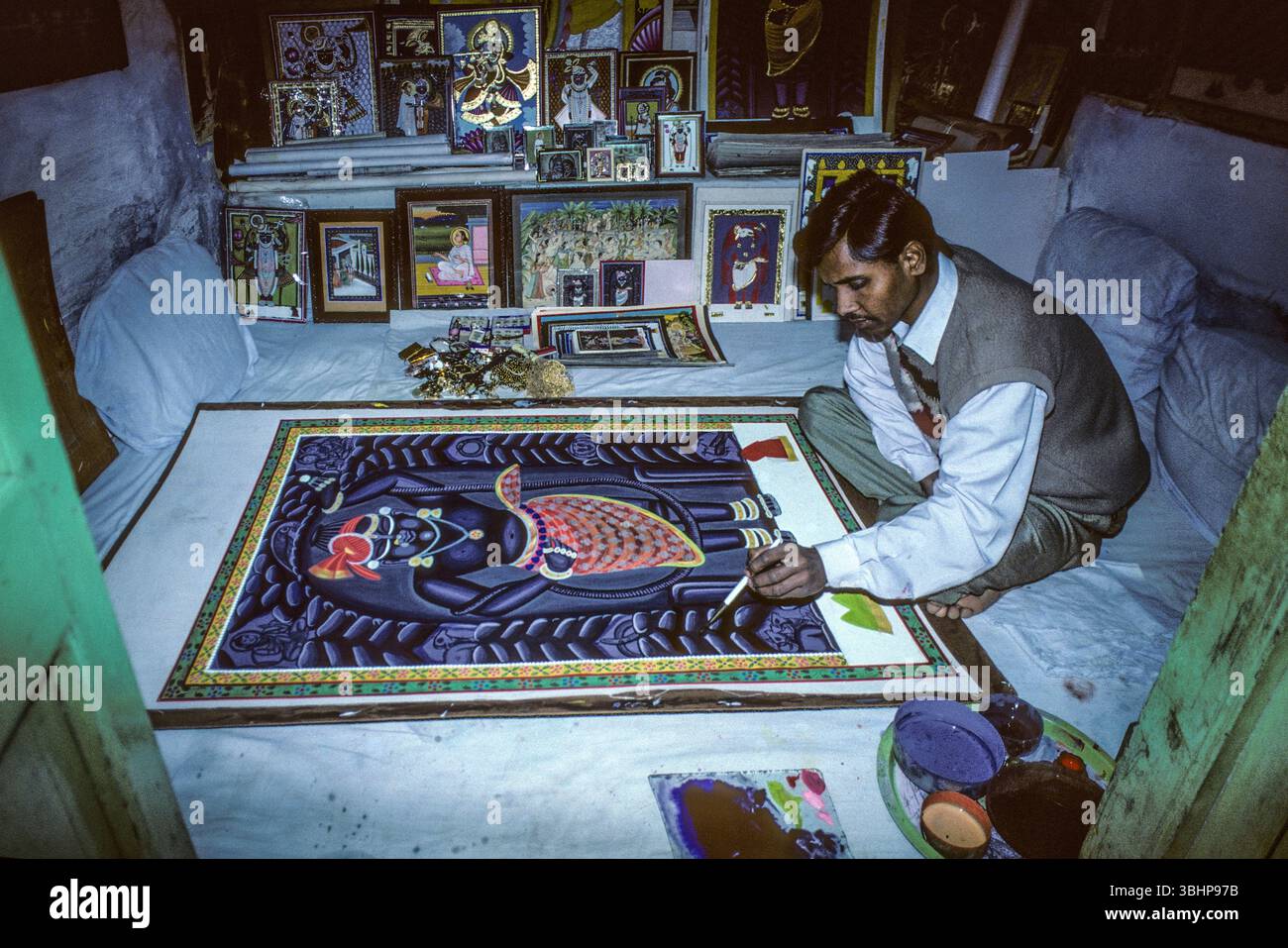 Nathdwara - La città è famosa perchè in questo luogo è nata e si è sviluppata una delle più ricche espressioni artistiche dell'India, le pitture 'pichwai', quadri rituali, riproduzioni iconografiche della leggenda del dio indù Krishna. SI tratta di dipinti su stoffa tessuta a mano ricamati con l'oro, stampati o dipinti su broccato. Nell'immagine un pittore all'Opera nella sua angusta abitazione Stockfoto Nathdwara - La città è famosa perchè in questo luogo è nata e si è sviluppata una delle più ricche espressioni artistiche dell'India, le pitture 'pichwai', quadri rituali, riproduzioni iconografiche della leggenda del dio indù Krishna. SI tratta di dipinti su stoffa tessuta a mano ricamati con l'oro, stampati o dipinti su broccato. Nell'immagine un pittore all'Opera nella sua angusta abitazione Stockfoto