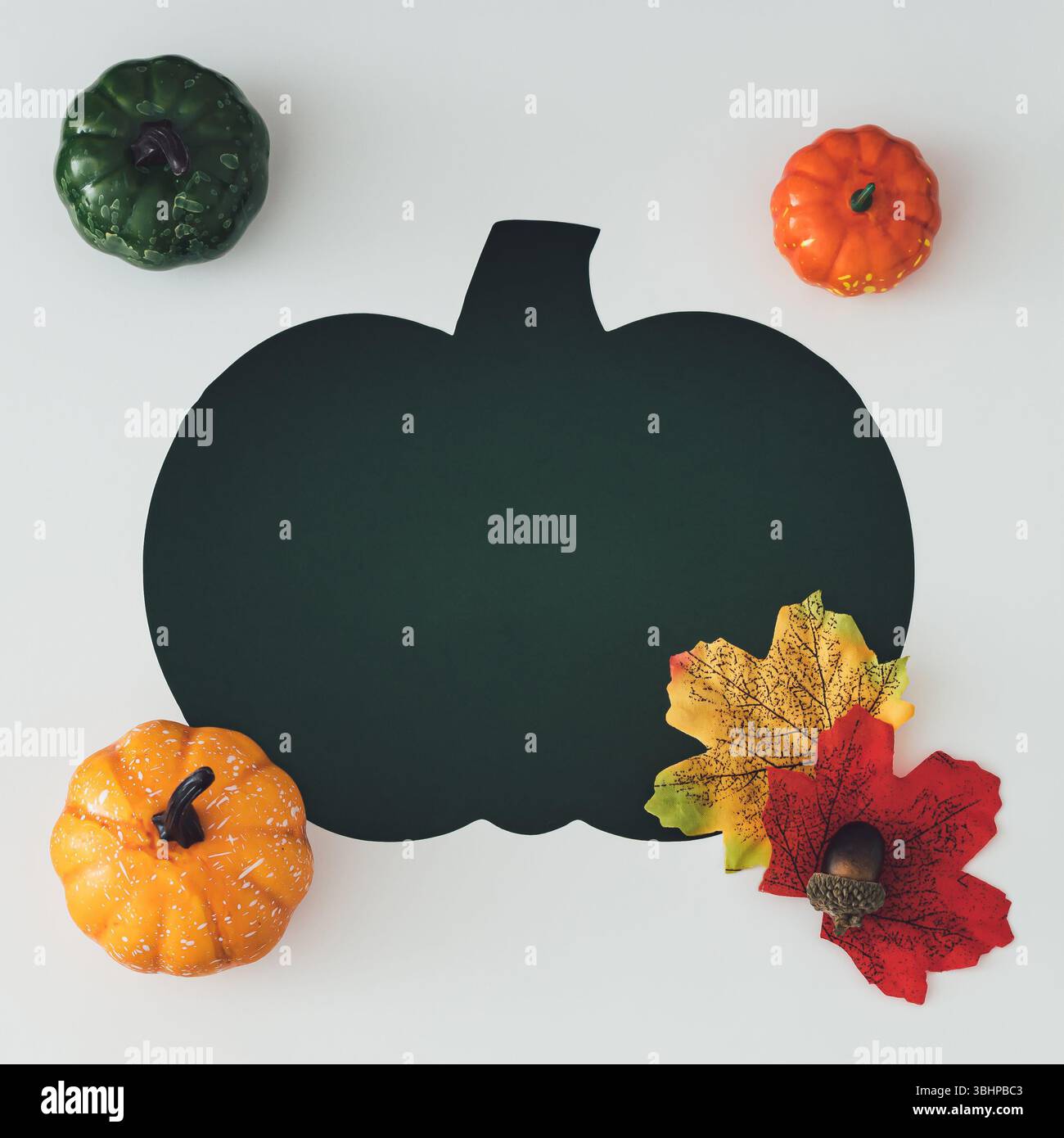 Flache Lage aus dekorativen Kürbissen, Eicheln, Herbstblättern und Kürbisausschnitt. Gemütliches saisonales Konzept für Herbsthintergründe und Thanksgiving-Themen. Stockfoto