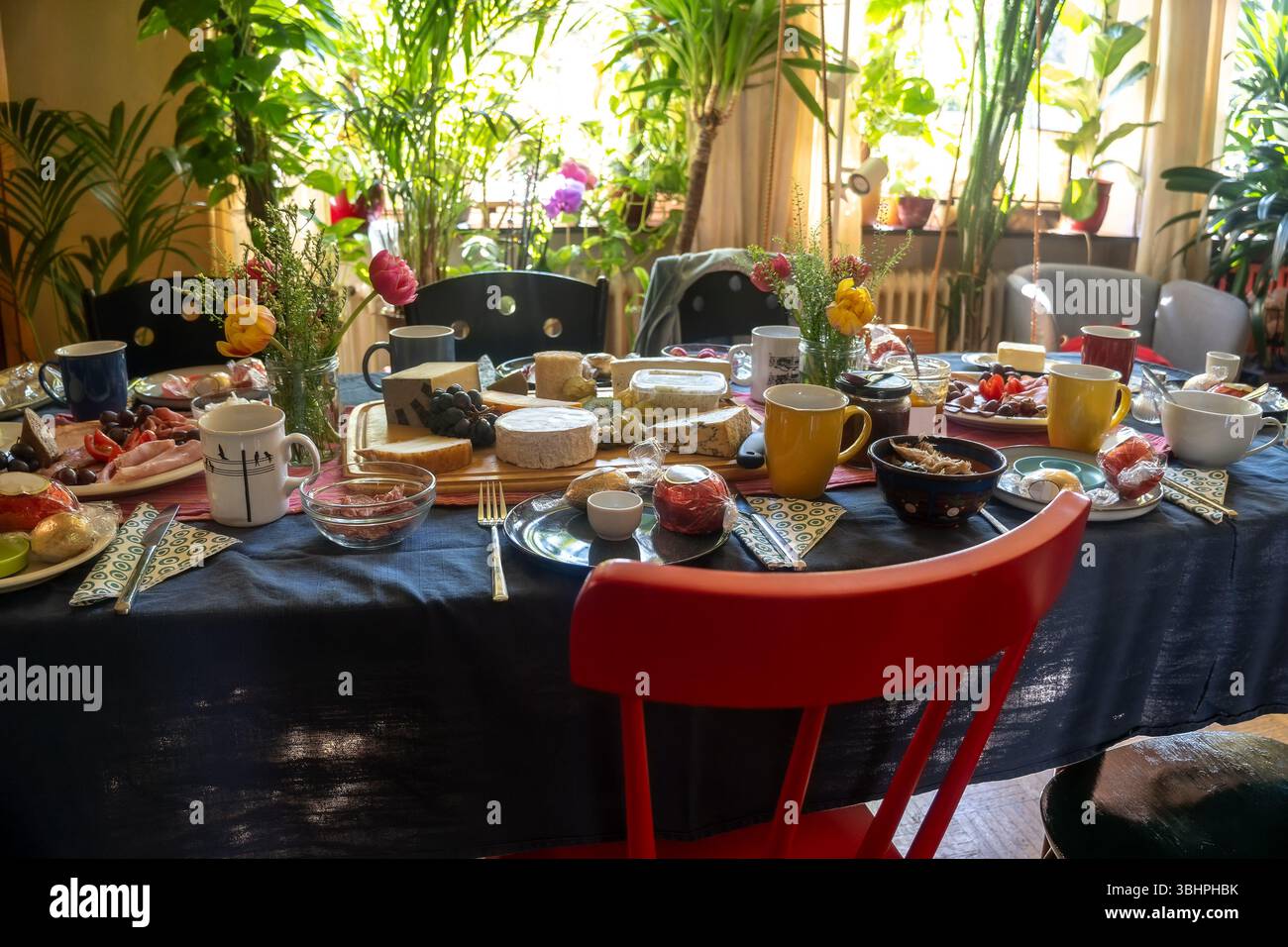 Großer Esstisch, komplett ausgestattet mit Käse, Wurst und weiteren Köstlichkeiten für ein Essen mit Familie oder Freunden im Wohnzimmer, ausgewählt, schmaler Platz Stockfoto