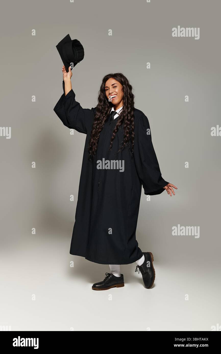 Der junge und schöne Schüler strahlt Glück aus, während er den Abschluss in formeller Kleidung feiert. Stockfoto