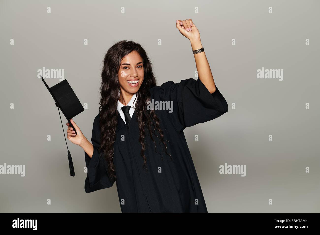 Eine junge Frau im Abschlusskleid feiert ihre akademische Leistung mit einem Hut Stockfoto