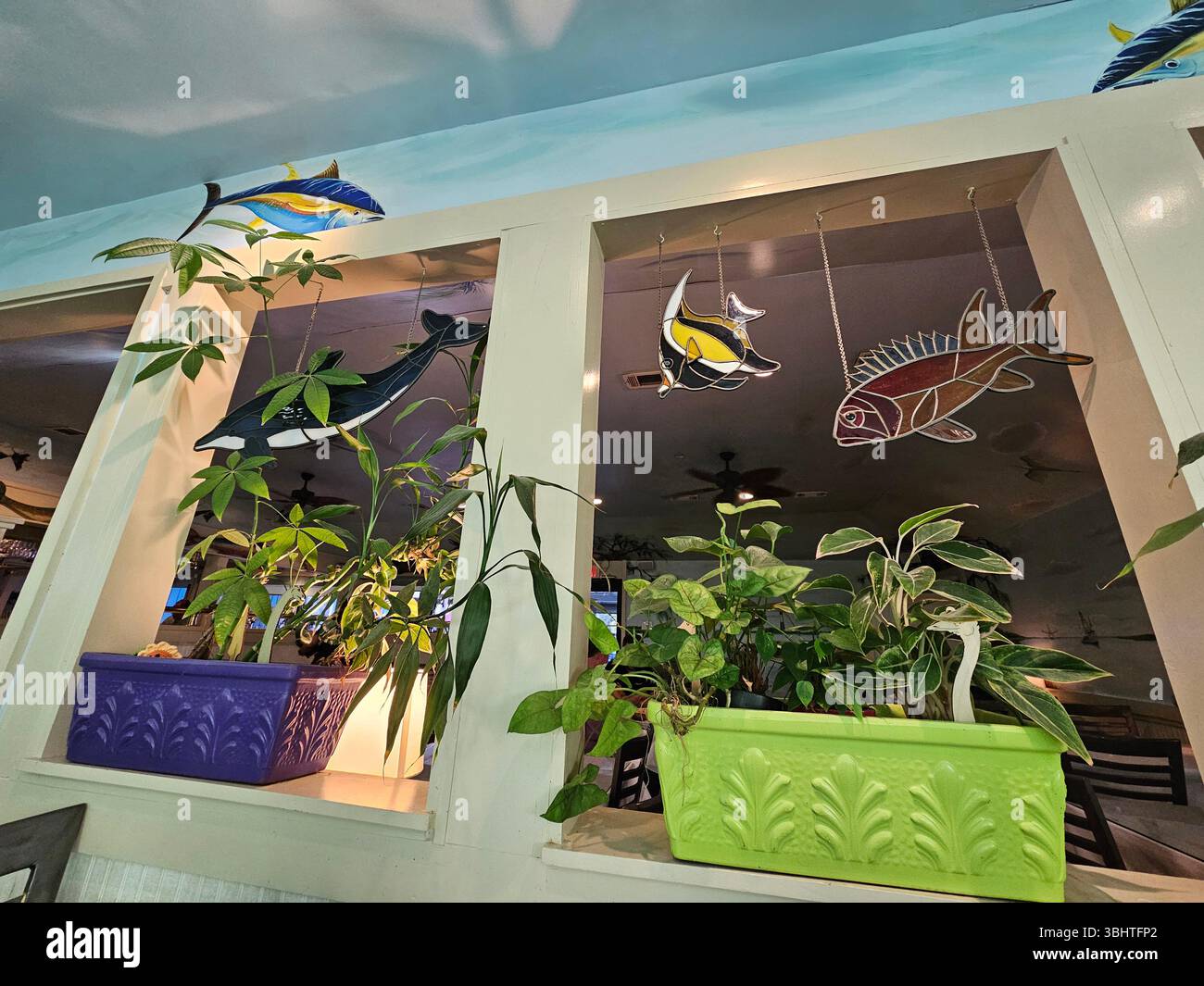 Bezaubernde Inneneinrichtung des Driftaway Cafe, Isle of Hope, Georgia. Hängende Fische aus Buntglas ergänzen die Gemälde an Wänden und Decken und Stockfoto