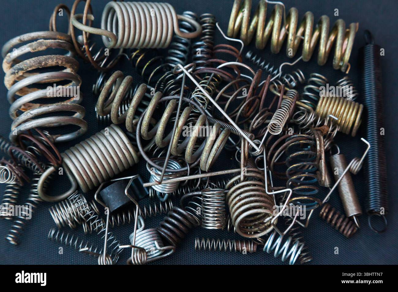 Viele kleine Federn unterschiedlicher Größe liegen auf einem Haufen vor schwarzem Hintergrund. Stockfoto