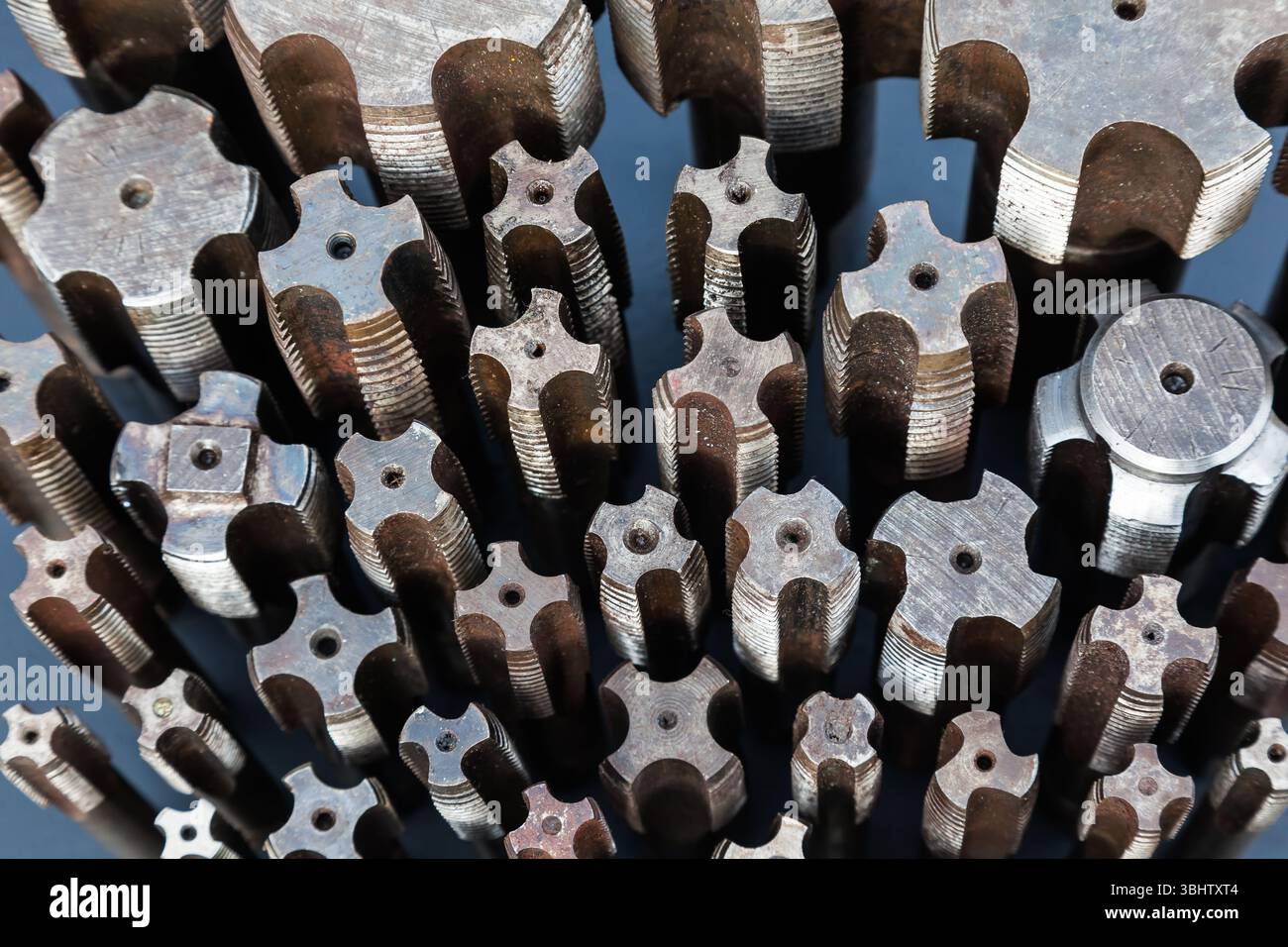 Viele Gewindebohrer unterschiedlicher Größe werden von oben aus auf eine schwarze Oberfläche gestellt. Stockfoto