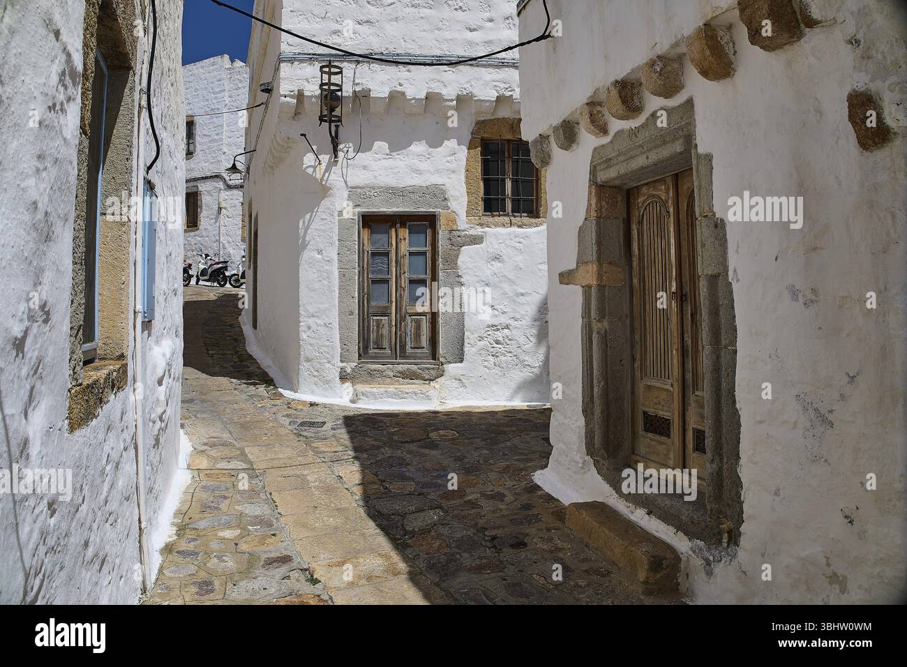 Enge, gepflasterte Gasse mit weißen historischen Gebäuden und Holzfenstern an einem sonnigen Tag, Mantomata Stones, Chora, UNESCO-Weltkulturerbe 1999, P Stockfoto