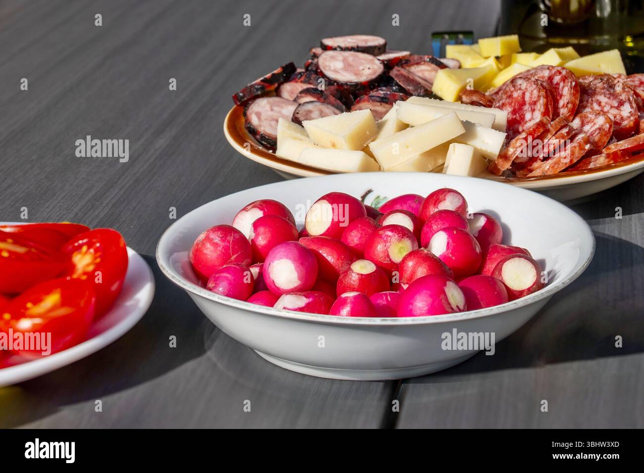 Drei Teller mit Tomaten, Rettich und verschiedenen Käsesorten, Wurst und Speck. Vorspeise, Imbiss oder kaltes Abendessen. Stockfoto