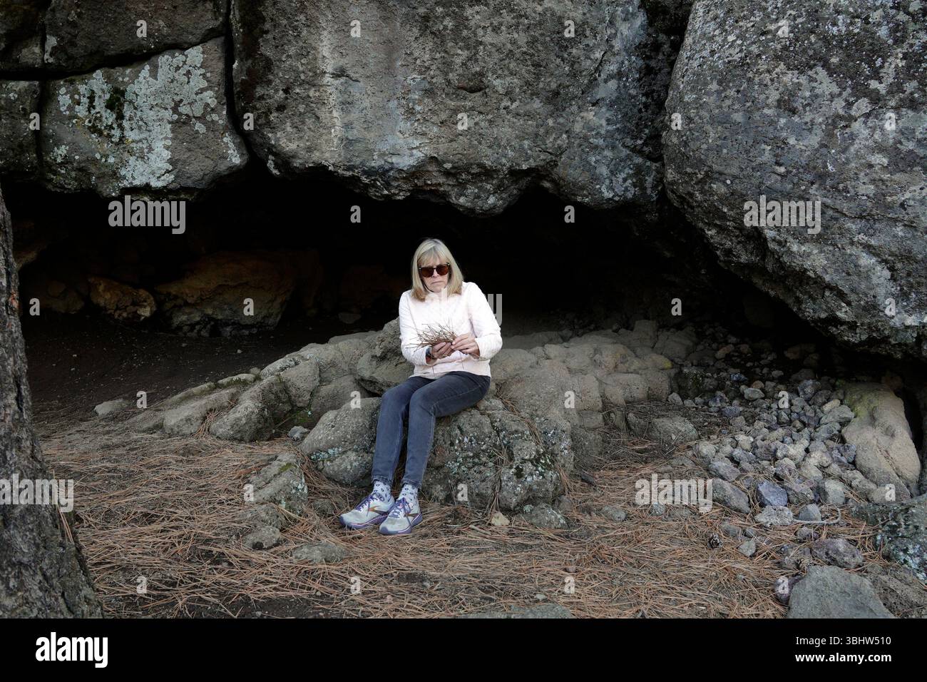 Ein Wanderer sitzt am Eingang des Little Lava Island Rock Shelter am Deschutes River, einer Lavahöhle, die von Familien der neolithischen Ind besetzt wurde Stockfoto