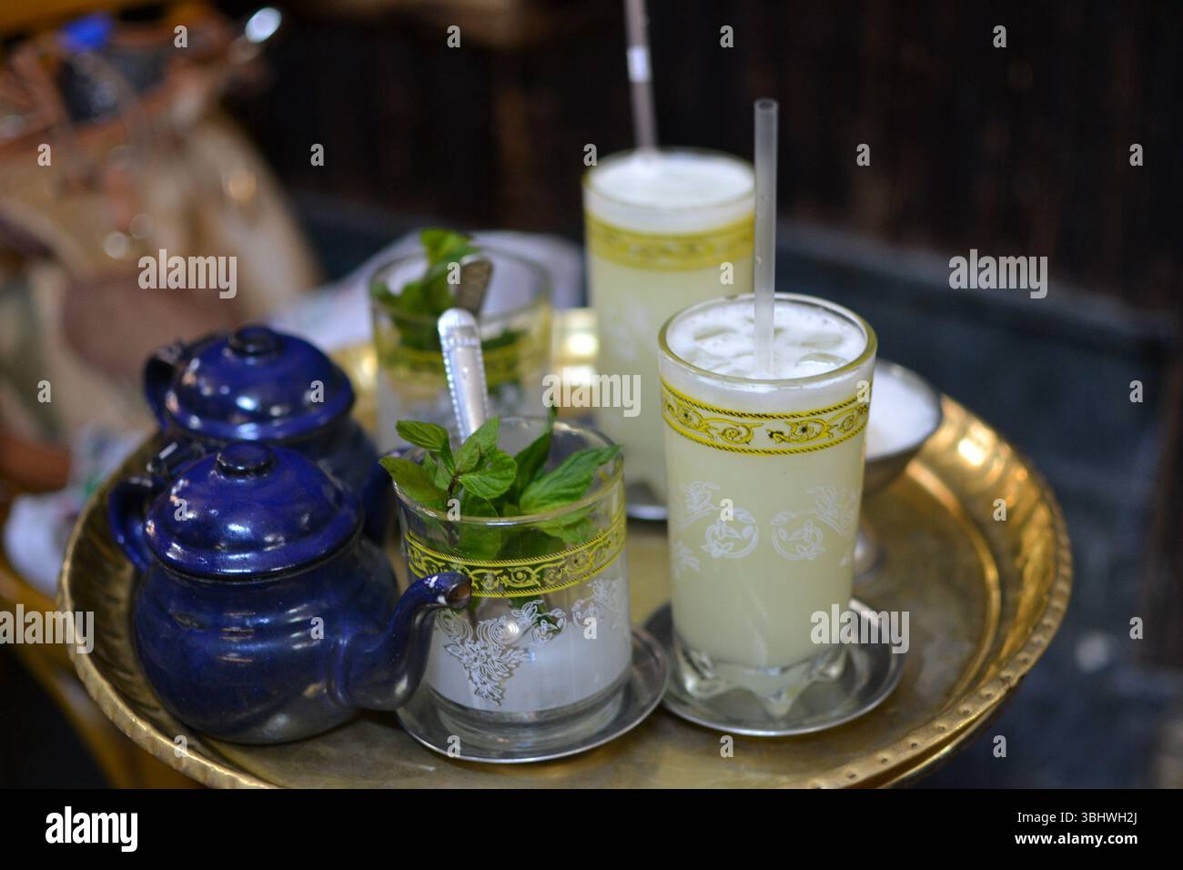Traditioneller marokkanischer Pfefferminztee, serviert in kunstvollen Gläsern auf einem goldenen Tablett. Stockfoto