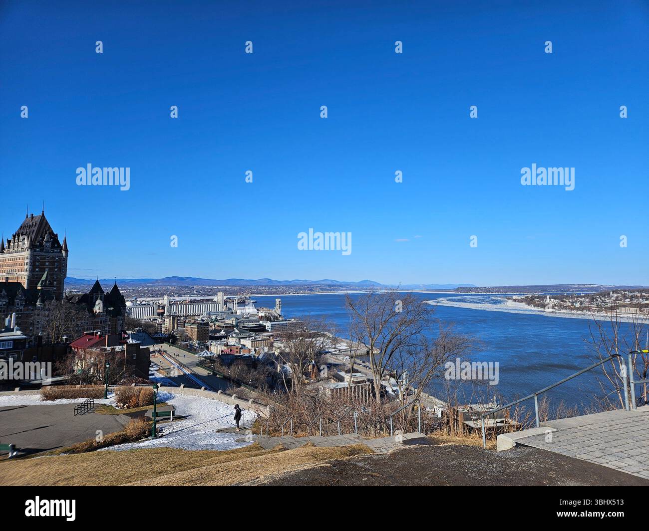 Malerisches Winterpanorama der Küstenstadt mit schneebedeckten Häusern mit Blick auf das Wasser der blauen Bucht und die fernen Berge unter klarem Himmel Stockfoto