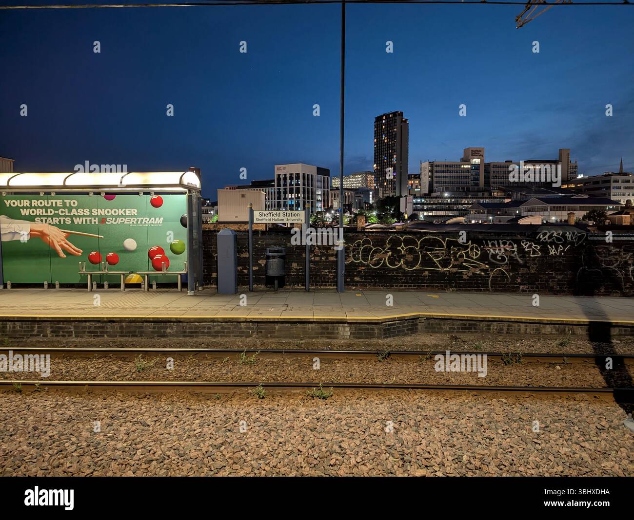 Eine atmosphärische Nachtszene in Sheffield. Das Stadtzentrum, das von Lichtern um die Straßenbahnschienen des Bahnhofs erstrahlt. Sheffield, eine Stadt, die für Snooker bekannt ist. - Smartphone-aufgenommenes Stockfoto