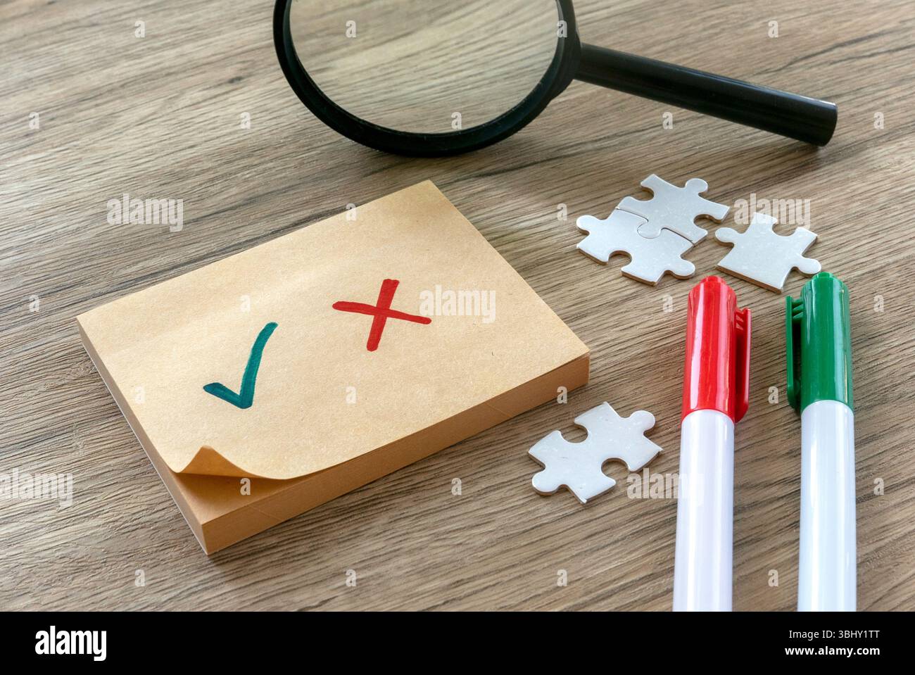 Checkliste mit grünem Häkchen und rotem Kreuz auf Haftnotiz mit Stiften und Vergrößerungsglas Stockfoto