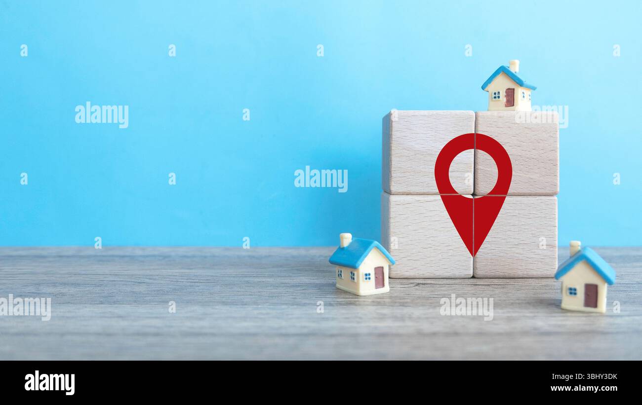 Holzwürfel mit Ortssymbol mit Miniaturhaus auf blauem Hintergrund mit Kopierraum. Stockfoto