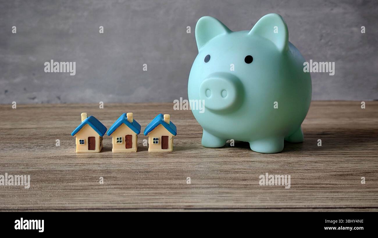 Symbolische Darstellung des Sparens für Immobilien mit Piggy Bank und Modellhäusern Stockfoto