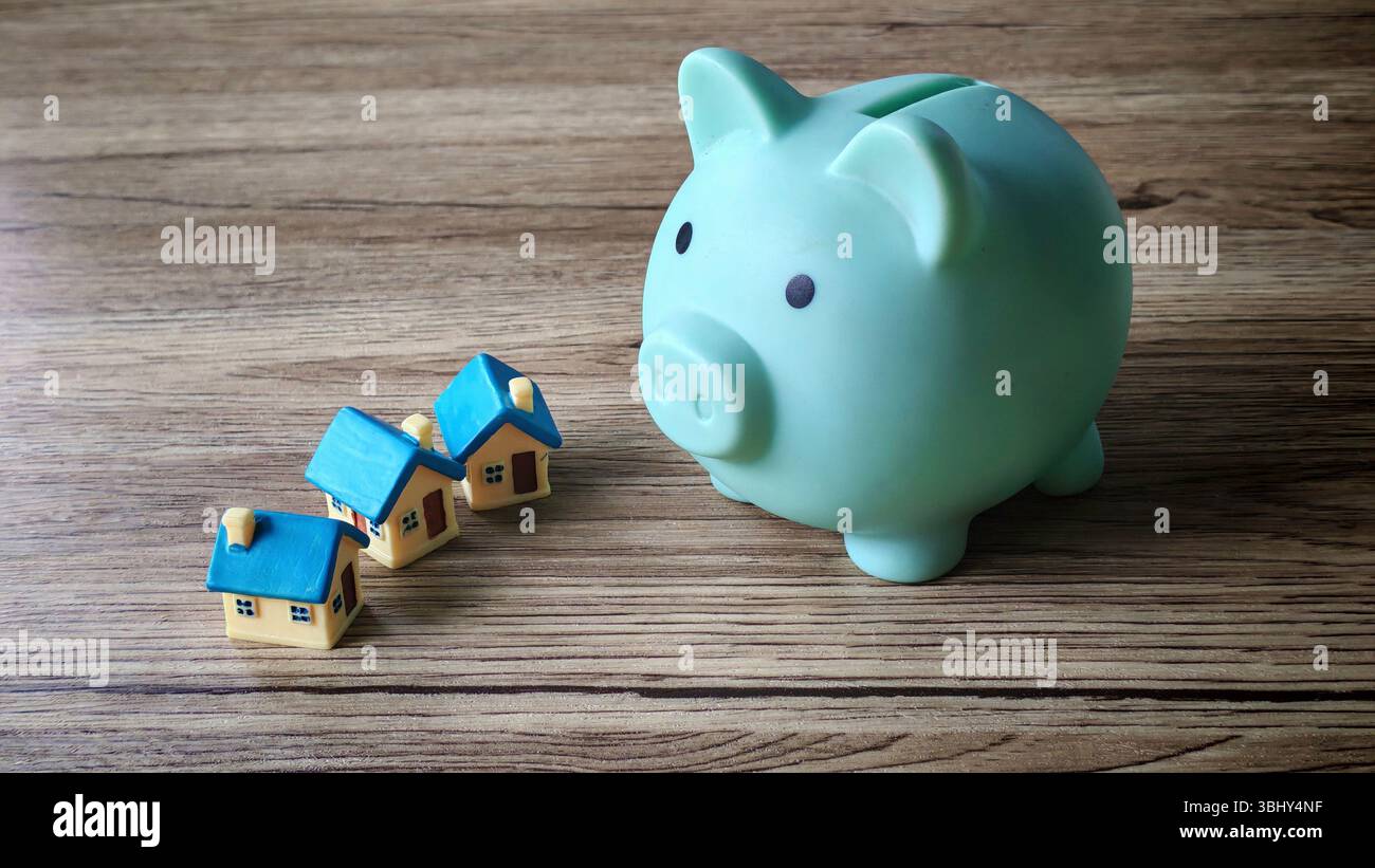 Symbolische Darstellung des Sparens für Immobilien mit Piggy Bank und Modellhäusern Stockfoto