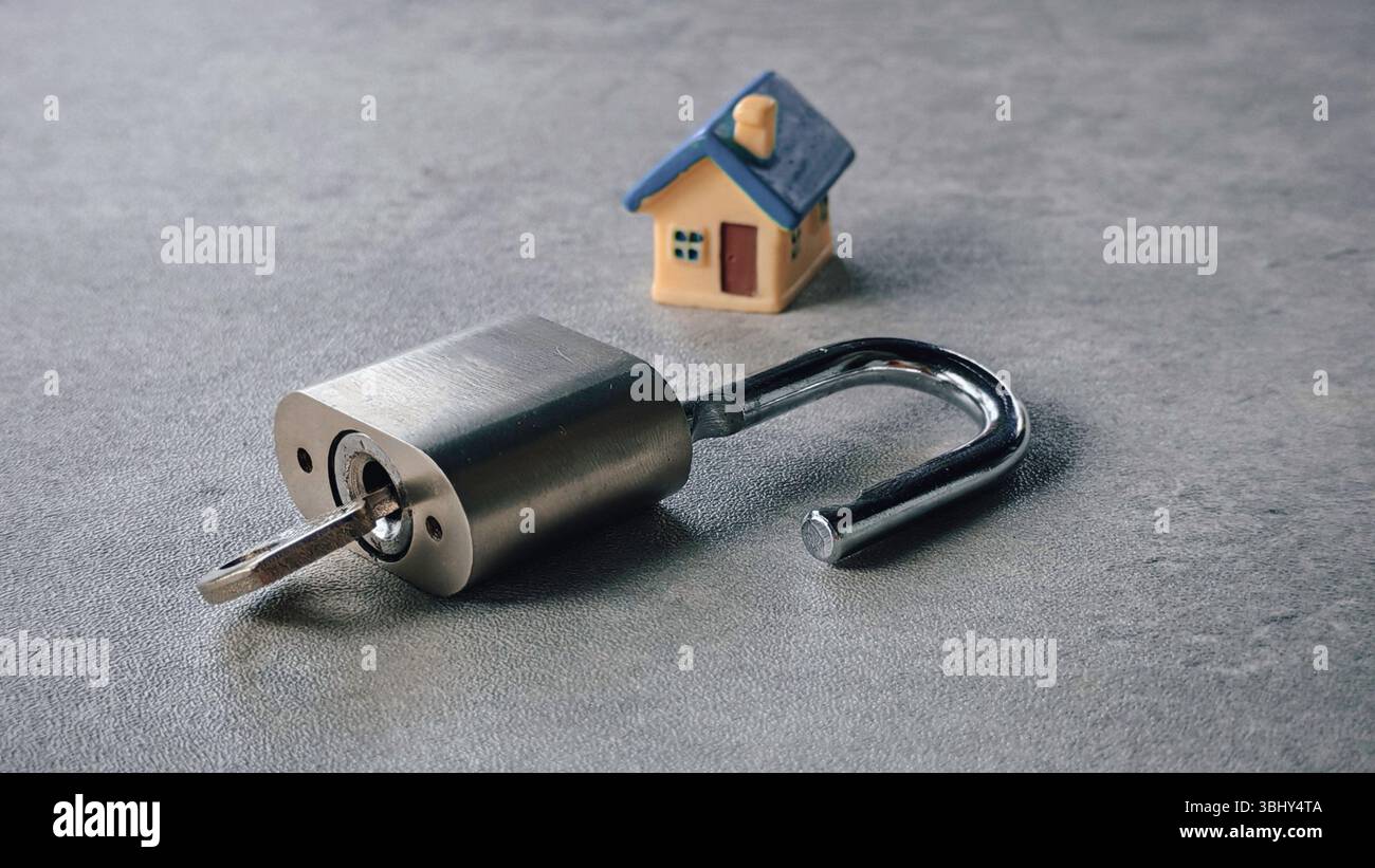 Entsperrtes Vorhängeschloss aus Metall mit Miniatur-Spielzeughaus Stockfoto
