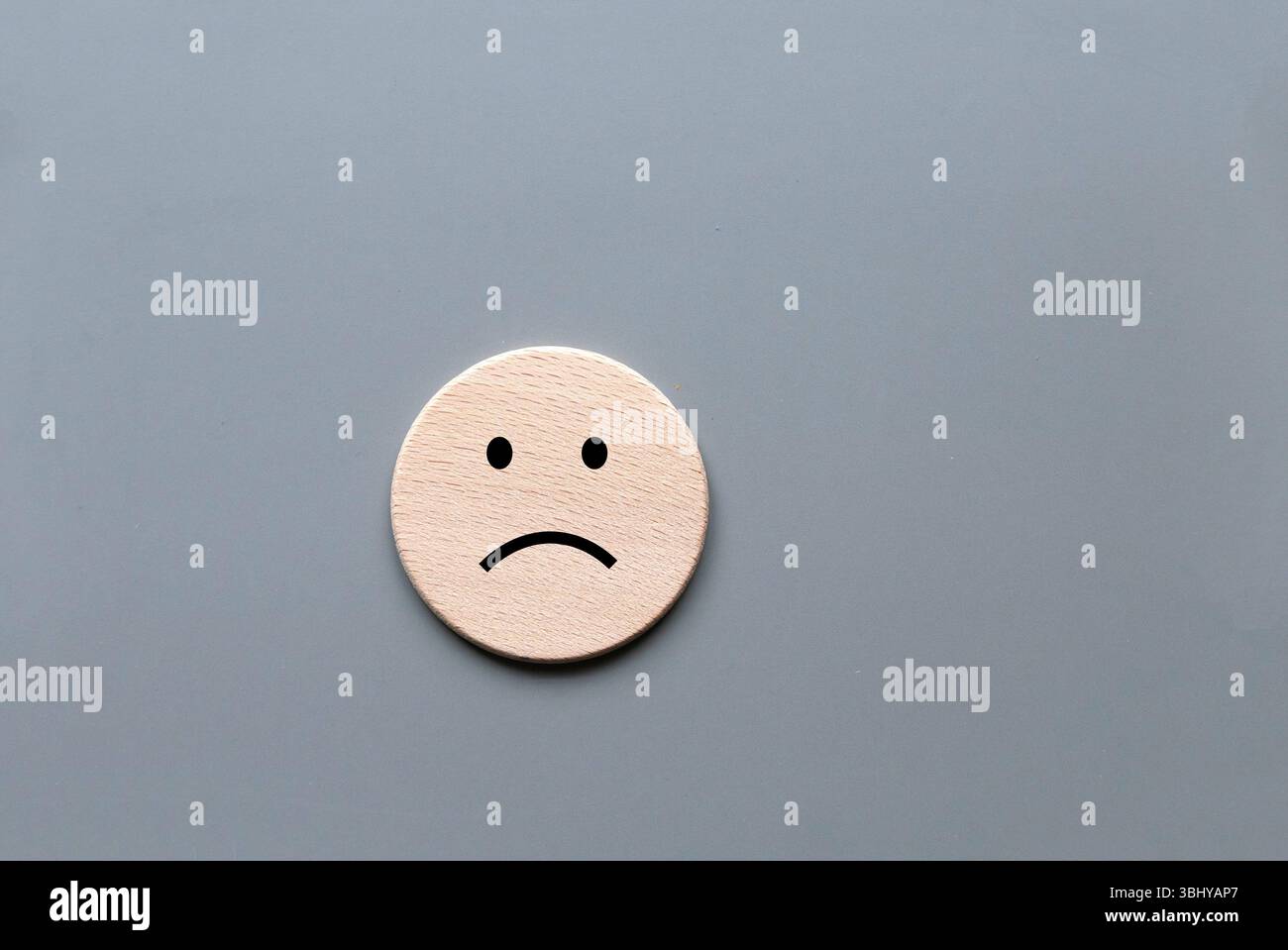 Hölzernes trauriges Gesicht Emoji auf grauem Hintergrund Stockfoto