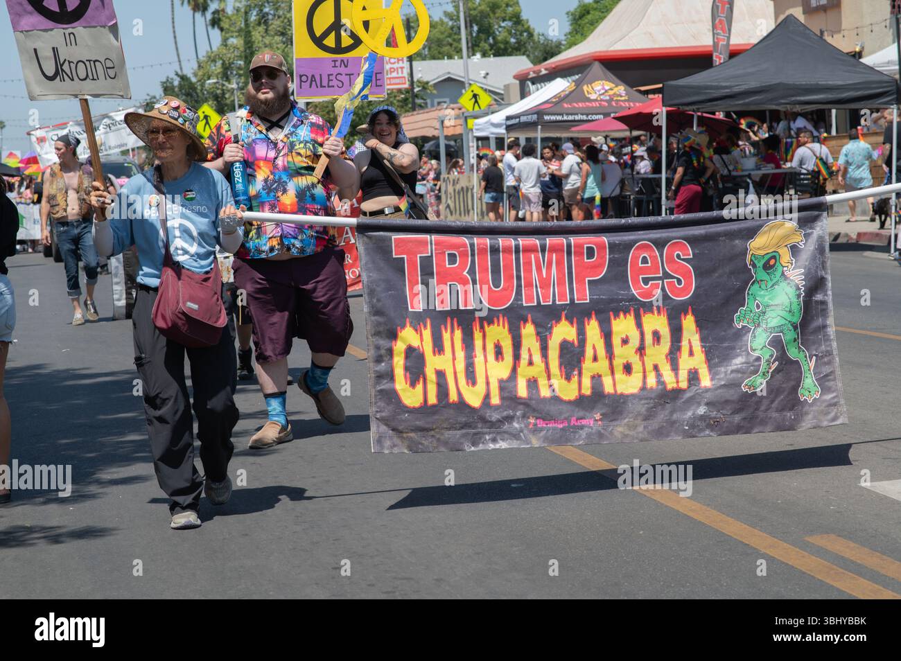 Ein Mitglied von Peace Fresno, das ein Banner über Präsident Trump bei Fresnos jährlicher Rainbow Pride Parade trägt. Eine Chupacabra ist ein mythisches blutsaugendes Monster Stockfoto