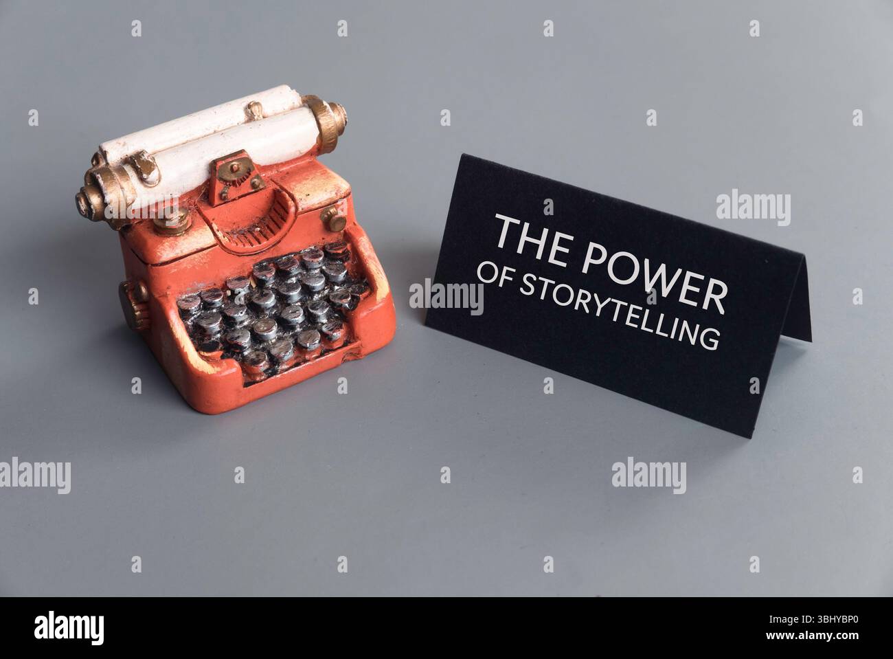 Vintage-Schreibmaschine mit „The Power of Storytelling“-Schild auf grauem Hintergrund Stockfoto