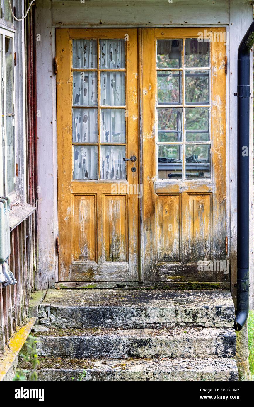 Holztür mit Fenstern auf einem alten verlassenen Häuschen Stockfoto
