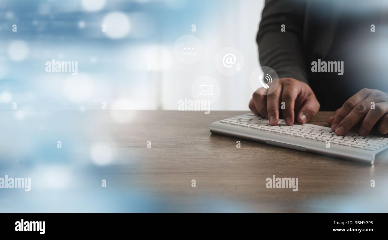 Eine Callcenter-Person, die eine drahtlose Tastatur mit digitalen Kommunikationssymbolen über der Tastatur eingibt, die Online-Kommunikation und digitale Kommunikation darstellen Stockfoto
