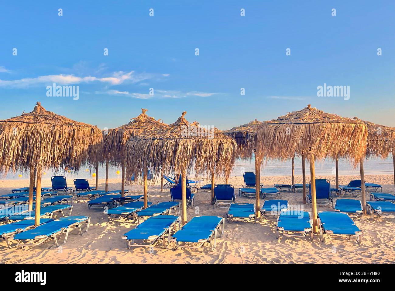 Chaotische Sonnenliegen und Sonnenschirme mit Palmenblättern am Strand Elafonissi, Kreta, Griechenland Stockfoto