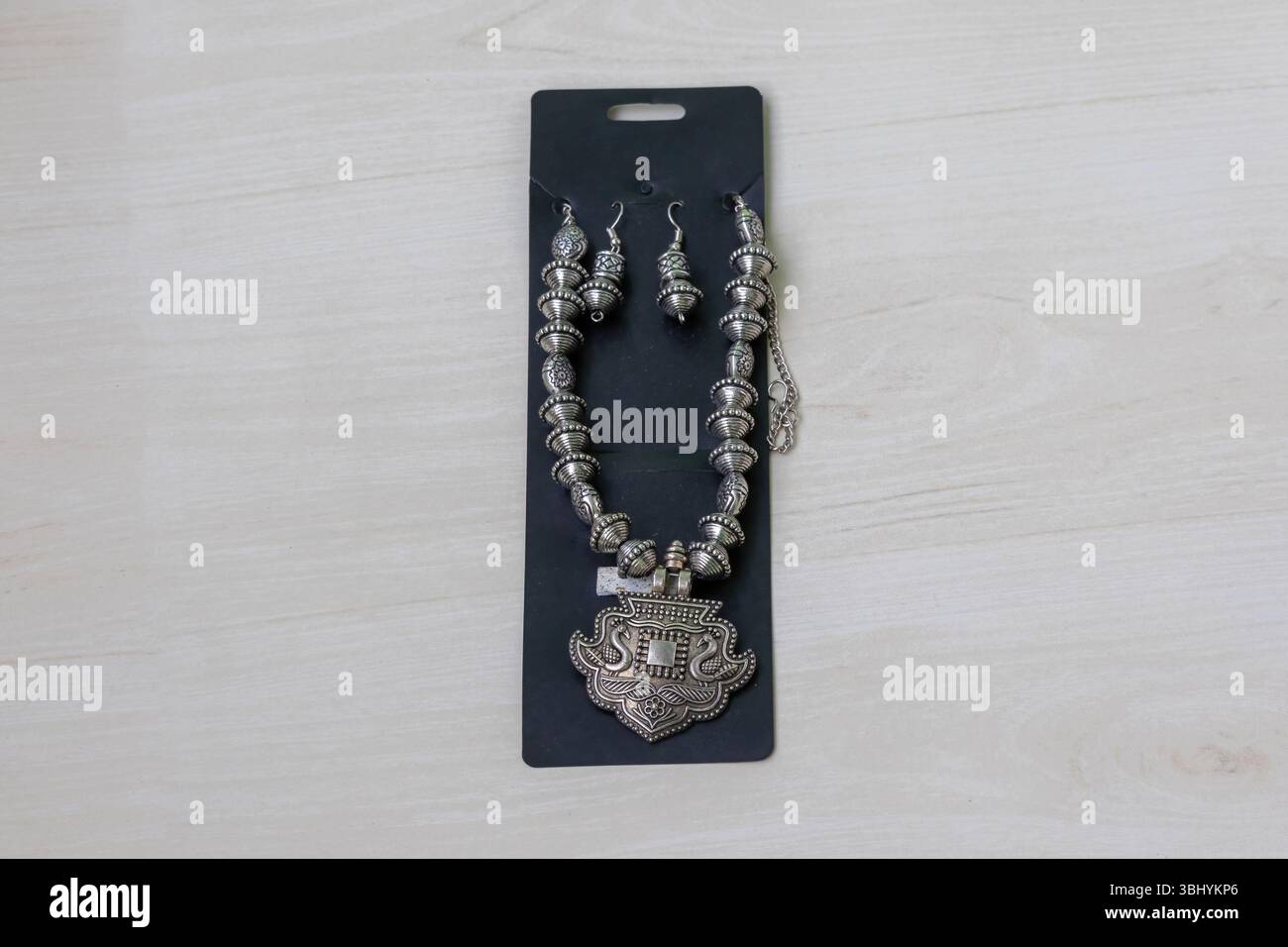Wunderschöne oxidierte Halskette und Ohrringe auf hölzernem Hintergrund. Damenschmuck-Accessoires im antiken Stil. Stockfoto
