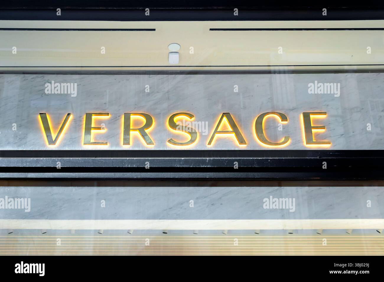 Beleuchtetes Versace-Logo-Schild an der Außenseite eines luxuriösen Modegeschäfts mit Marmorhintergrund manhattan New york Stockfoto