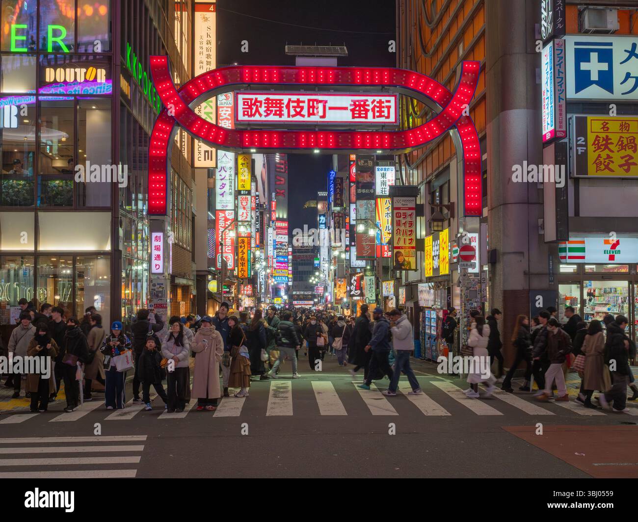 Neonlichter und Menschenmassen entlang einer Hauptstraße westlich des Bahnhofs Shinjuku, Tokio, Japan Stockfoto