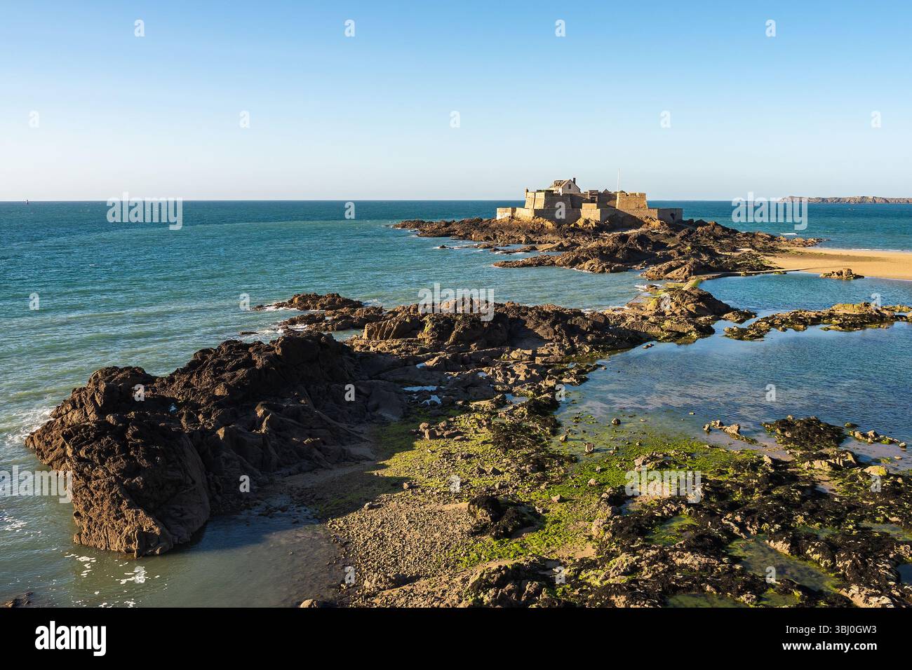 Panoramablick auf Fort National in Saint-Malo, Bretagne, Frankreich, von den Stadtmauern bei Ebbe mit Gezeitenbecken und felsiger Küste unter einer Clea gesehen Stockfoto