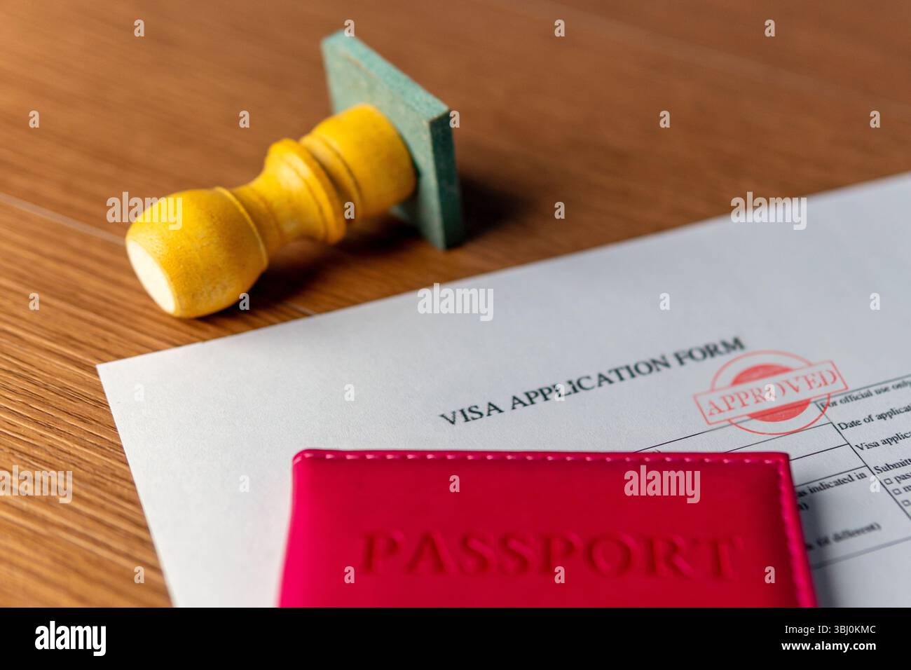 Ein Visumantragsformular mit „GENEHMIGTEM“ Stempel, einem roten Reisepass und einem Gummistempel. Internationale Reisen, Erlaubnis, offizielles Einwilligungskonzept. Stockfoto
