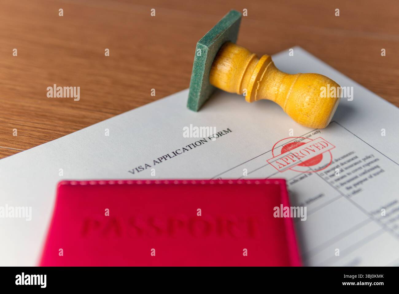 Ein Visumantragsformular mit „GENEHMIGTEM“ Stempel, einem roten Reisepass und einem Gummistempel. Internationale Reisen, Erlaubnis, offizielles Einwilligungskonzept. Stockfoto