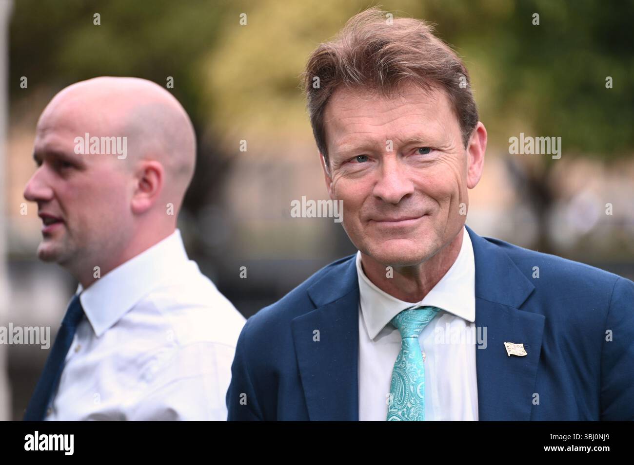Richard Tice Abgeordnete (Reform: Boston and Skegness) und Stephen Flynn (SNP-Chef in Westminster, dahinter) am College Green, Westminster, um Rachel Re zu diskutieren Stockfoto
