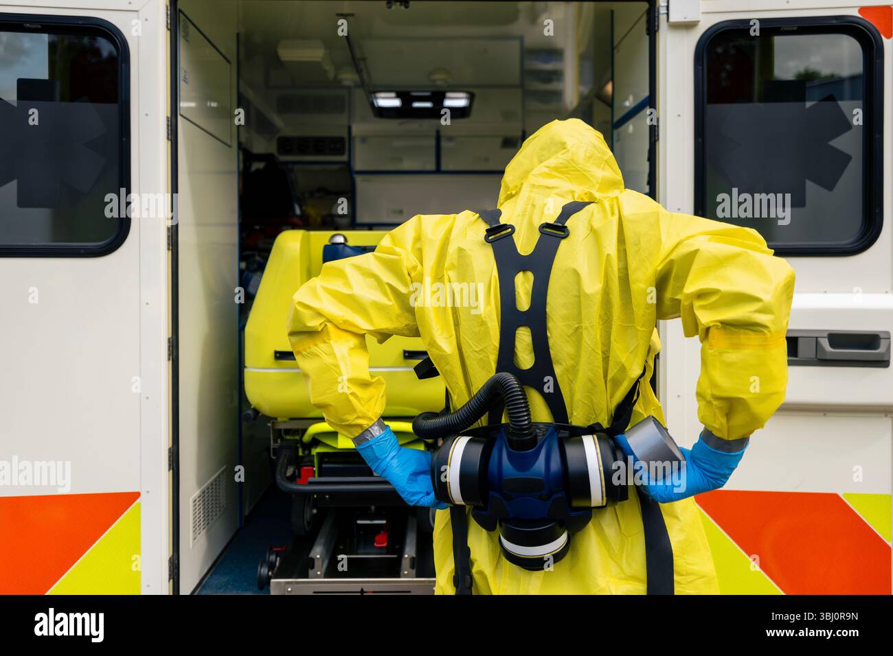 Mitglied des Biohazard-Teams des medizinischen Notdienstes in Schutzanzug gegen Krankenwagen. Stockfoto