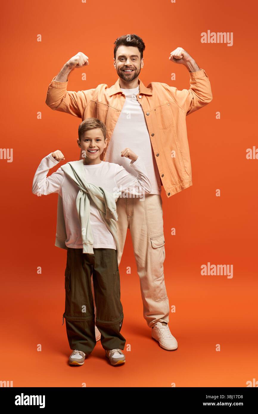 Vater und Sohn teilen einen stolzen Moment, indem sie ihre Muskeln in einer festlichen Atmosphäre zusammenspielen. Stockfoto