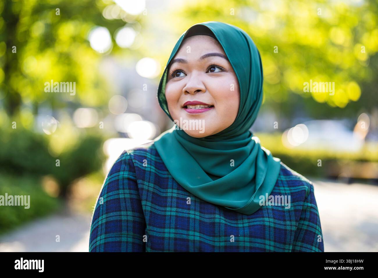 Porträt einer asiatischen muslimischen Frau, die Hijab trägt und vor der Kamera lächelt Stockfoto