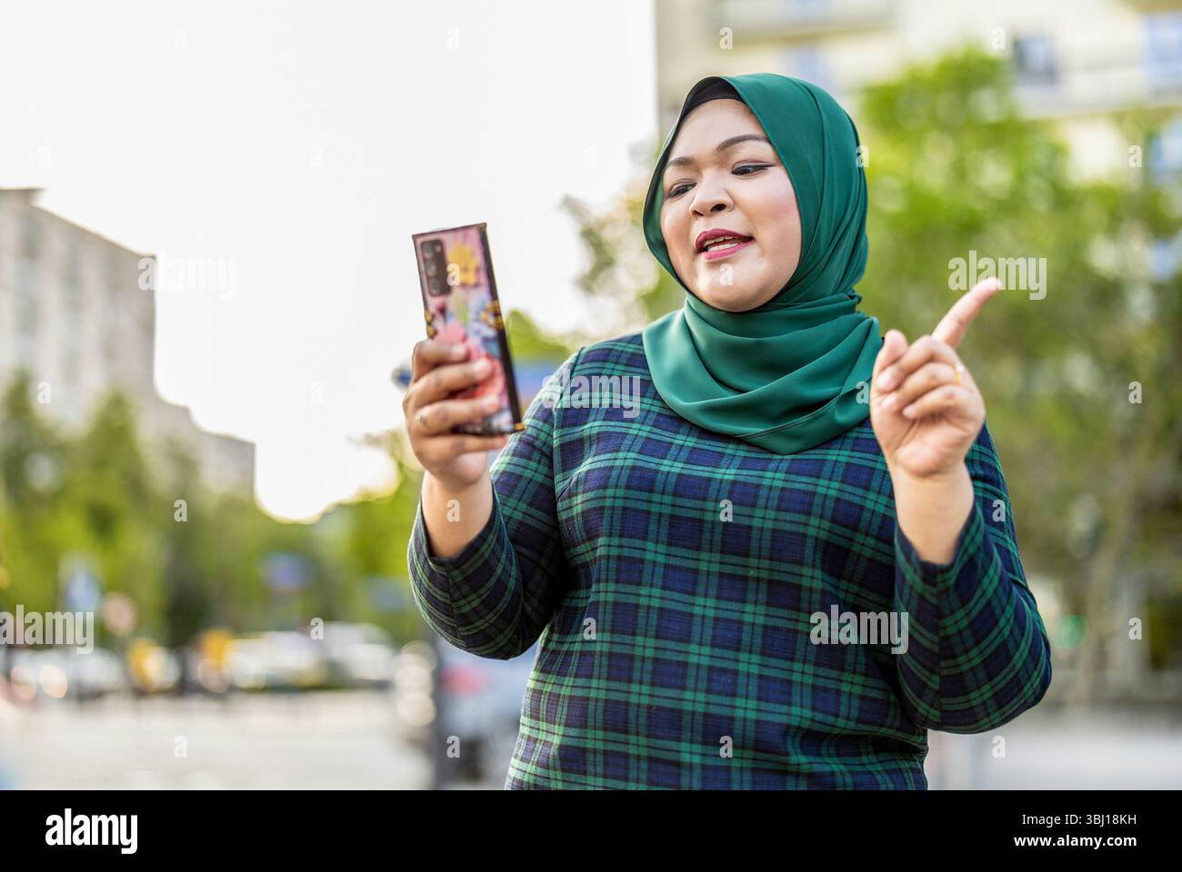Muslimische Frau hat Videoanrufe per Handy in der Stadt Stockfoto
