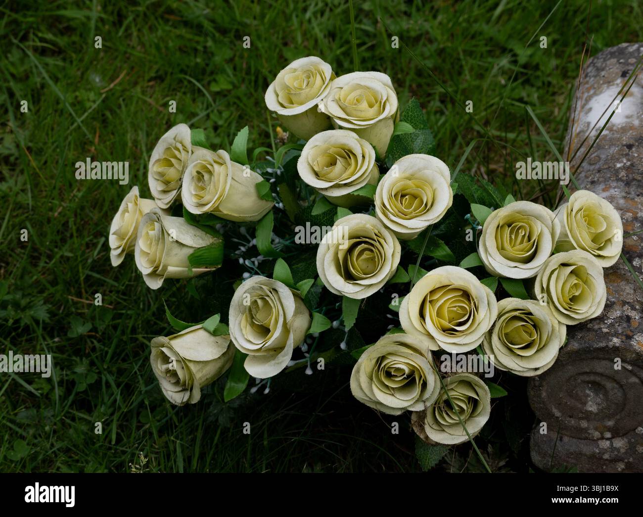Achtzehn künstliche Rosenblüten auf einem Grab, Großbritannien Stockfoto