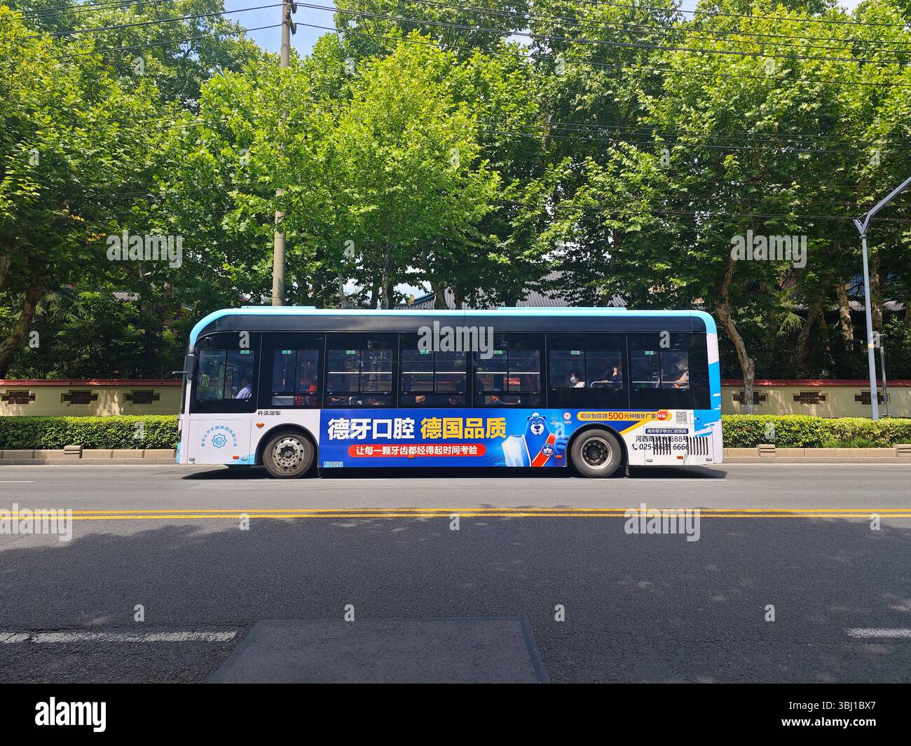 Nanjing, China - 5. Juni 2025: Ein blauer Bus auf der Straße am sonnigen Tag in Nanjing Stockfoto