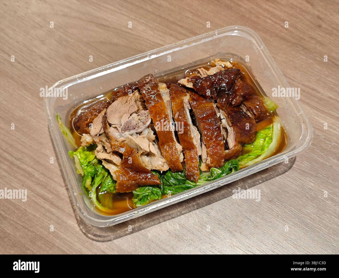 Frisch gebratene Gans mit grünem Gemüse im Kunststoff auf dem Holztisch Stockfoto