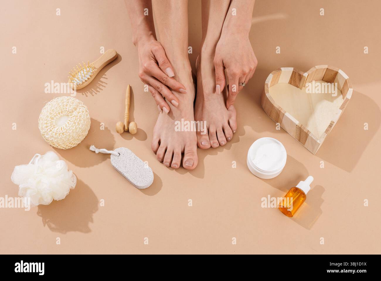 Flache Lagen von weiblichen Füßen und Selbstpflegegeräten einschließlich Creme, Bürste, Öl und Bimsstein. Konzept der Fusshautpflege, Spa-Behandlung und Beauty-Routine Stockfoto